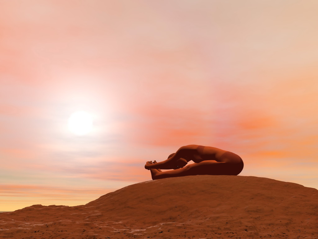 Young woman doing seated forward bend pose, paschimottanasana, while practicing yoga outside in front of sunset