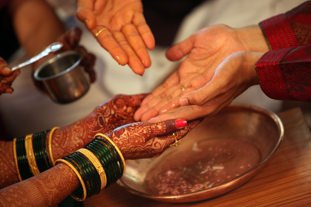 The hands of bride and groom being washed with holy water in a traditional Hindu wedding ritual