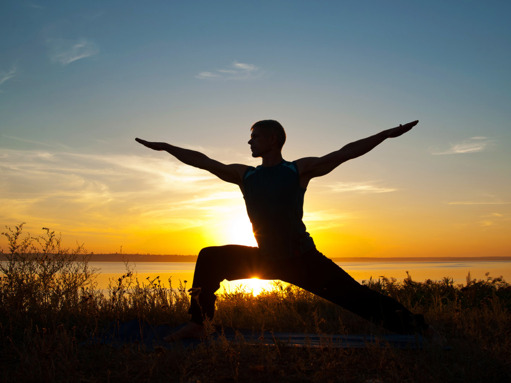 Man in yoga warrior pose standing outdoors